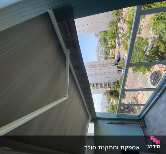סוכך אפור עם זרועות מתכת במרפסת